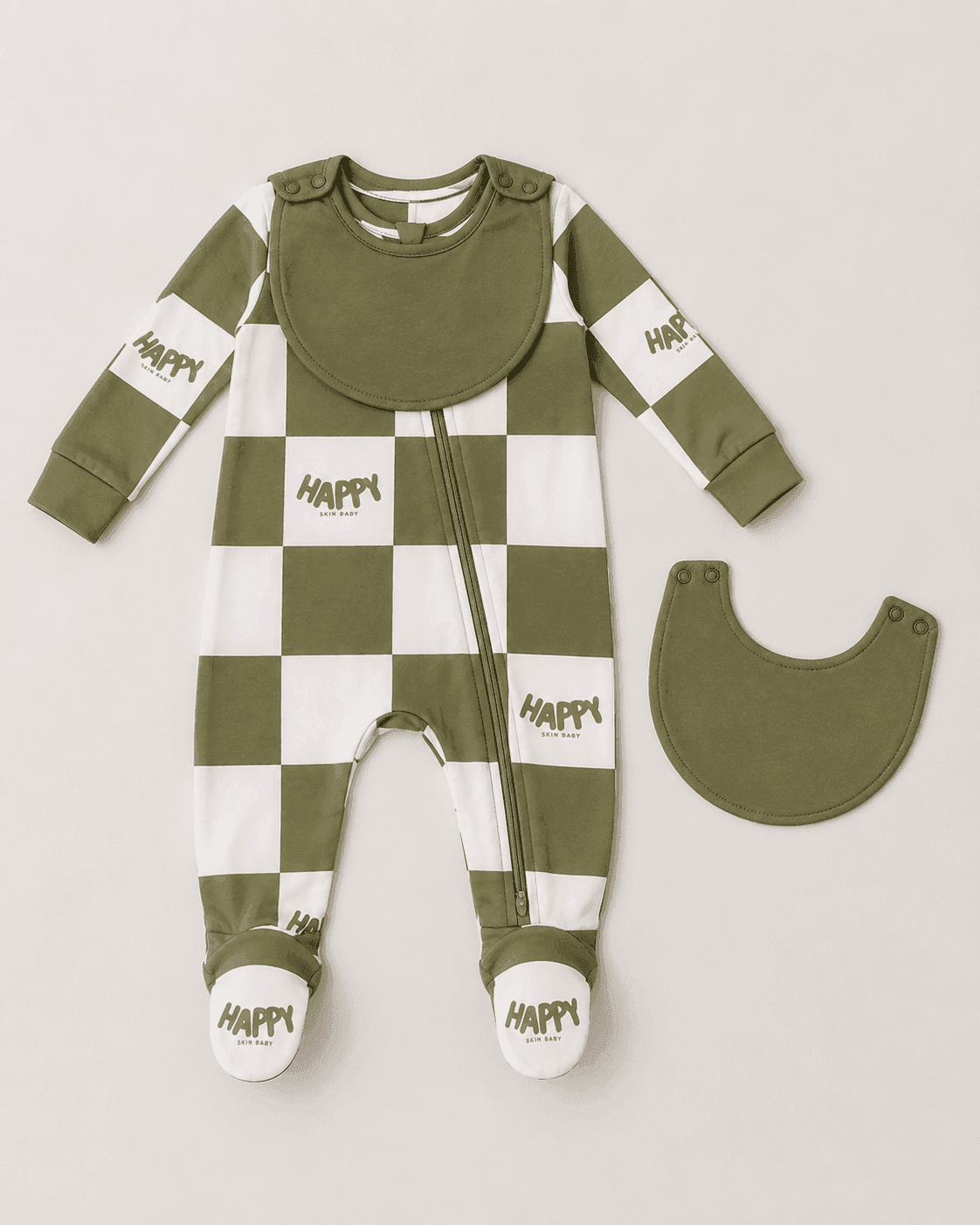 The Everything Zippy footed pajama with its bib snapped on, shown next to a second bib detached, demonstrating the removable attached bib